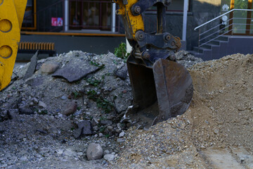Excavator digging at construction site near building during daytime in urban setting