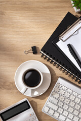 A morning workspace with a keyboard, notebook, coffee, calculator, plant, pen, eraser, and crumpled...