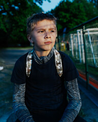 Boy wearing a black shirt that says Stay True sits on the ground