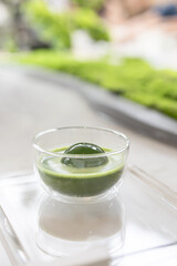 Matcha or green tea latte in transparent glass with round ice, also known as ice spheres