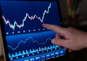 Finger pointing at a stock market chart on a computer screen. Trading board, stock exchange,...