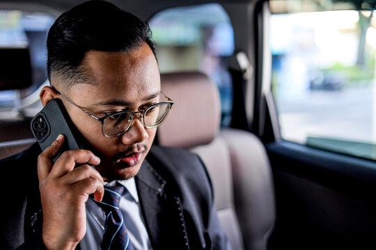 Young Businessman In Suit Talking On Smartphone While Seated In Car