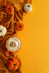 Pumpkin latte with whipped cream and spices, surrounded by autumn decor. Top view. Copy space