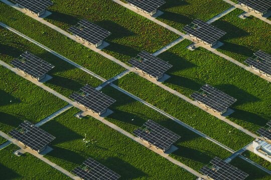 View of solar panels glinting under the sun, contrasted by the vibrant green grass, creating a geometric tapestry of energy and nature, New York, United States.