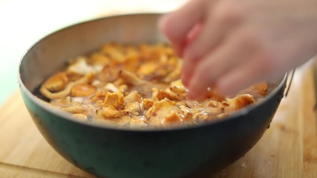 A woman washes fresh chanterelle mushrooms in her home kitchen sink, preparing ingredients for a delicious homemade lunch.