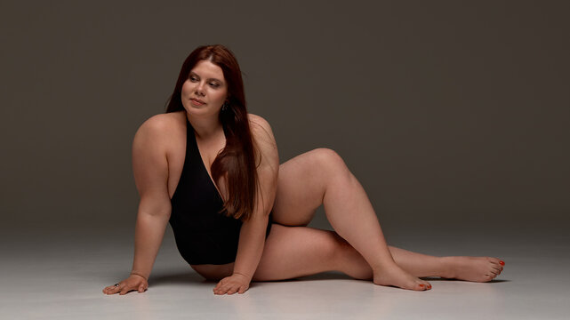 A plus-size woman confidently poses in a black swimsuit, promoting body positivity and empowerment. Concept of embracing self-image and diversity in fashion.