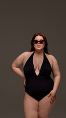 A plus-size woman confidently models stylish black swimwear paired with chic sunglasses. Concept of...