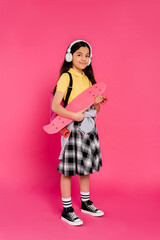 Stylish preteen girl ready for school in vibrant studio with skateboard