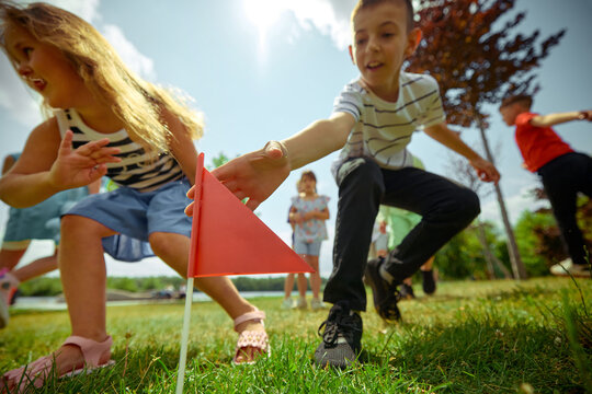 Group of children playing capture the flag outdoors on a sunny day, showcasing teamwork, active play, and joyful childhood moments in a natural park setting.
