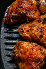 Baked chicken thighs on a cast iron grill pan with a crispy crust