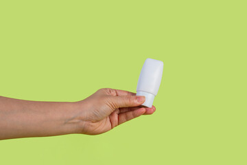 Skin care or sunscreen cosmetic and hand on green background.