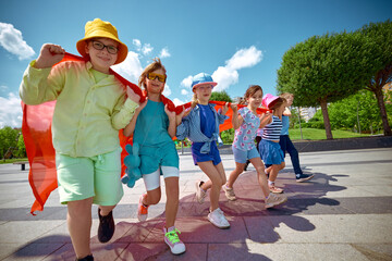 Kids wear capes and enjoy the sunshine outside, embodying childhood adventure and imagination....