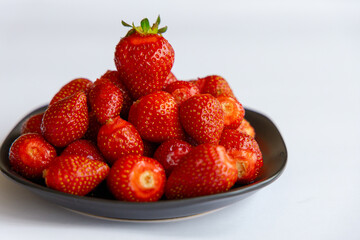 Juicy seasonal strawberries close up macro texture on a black plate