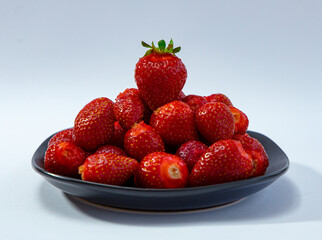 Juicy seasonal strawberries close up macro texture on a black plate