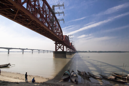 Pabna, Bangladesh - 27 November 2022: View of the stark red girders of the Hardinge Bridge contrasting against the soft, muted tones of the Padma River.
