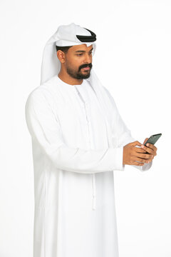 Portrait of an emirati man on a white background using mobile.