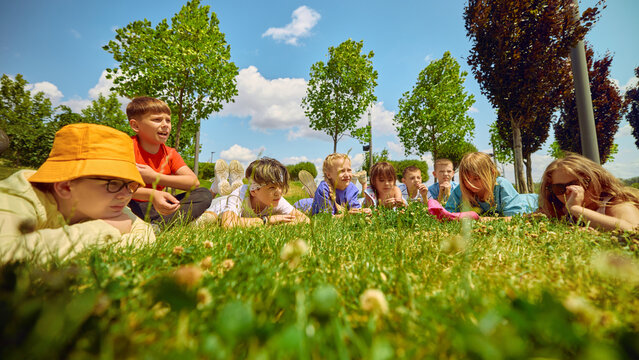 Children rest on the grass beneath a sunny sky in the park, enjoying the warmth and the beauty of nature. Idea centered on outdoor leisure and play.
