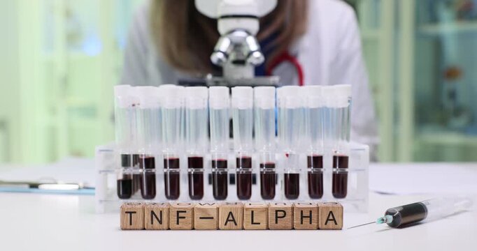 A scientist is carefully examining TNFalpha blood samples using a powerful microscope in a modern laboratory
