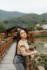 A woman stands on a wooden bridge near a pond.