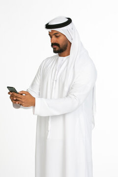 Portrait of an emirati man on a white background using mobile.