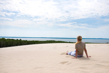 Fototapeta premium Young woman tourist sitting in sand on beautiful beach Baltic Sea
