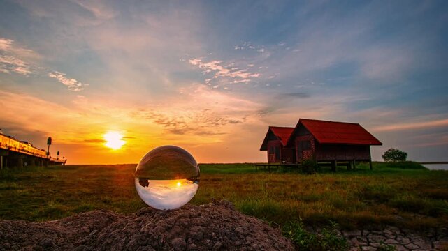 The day begins with a gentle glow as the sun lifts above the horizon. a glass ball mirrors the world in miniature: the lakeside duplex, the concrete bridge, and the radiant sky turned upside down.