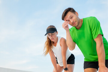 Exhausted runners take a break during an afternoon workout at a sunny outdoor training facility