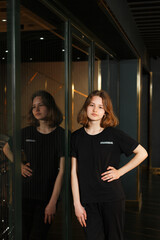 Girl in black pants and dark t-shirt near mirror window