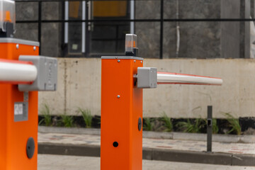 Two orange parking barrier gates stand in an outdoor parking lot