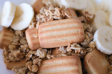 Plate with baby biscuits, honey almond granola, and banana.
