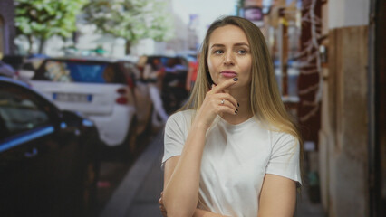 Fototapeta premium Woman contemplating on street with cars and buildings in a cityscape background under bright daylight.