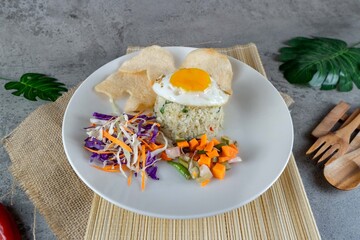 Traditional Indonesian Fried Rice with Egg Served on White Plate with Pickles and Crackers