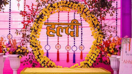 Vibrant Indian Haldi ceremony backdrop adorned with yellow and orange flowers, traditional decor,...