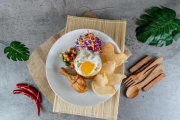 Traditional Indonesian Chicken Fried Rice Served on White Plate with Pickles and Crackers