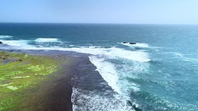 Drone aerial footage showing a small tropical island surrounded by turquoise sea, clear shallow water, and gentle waves under bright sunny weather. Perfect for travel, nature, and coastal landscape.
