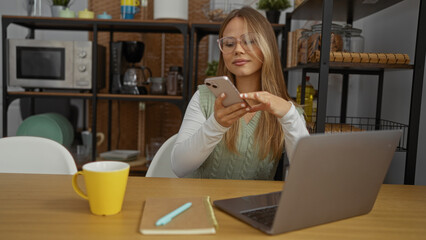 Woman scrolls smartphone at apartment desk beside a yellow mug and laptop on a wooden table; serenity connection productivity focus.