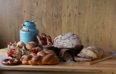 Traditional bakery products no. 6 in an organized composition. Bread, loaves, rolls, croissants, pretzels, challah, ears of grain, baked goods, a blue metal watering can, traditional table decoration