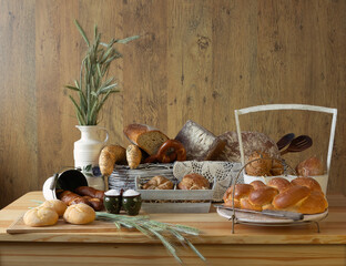 Traditional bakery products no. 5 in an organized composition. Bread, loaves, rolls, croissants, pretzels, challah, ears of grain, baked goods, porcelain jug, wooden spoons, traditional decoration