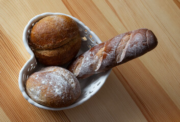 fresh bread on a wooden table in a porcelain dish, a delicious breakfast for morning coffee, baguette and rolls on a porcelain plate
