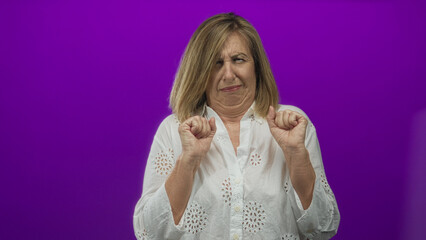 Caucasian middle age woman wearing white blouse with raised hands pushing forward in purple studio;...
