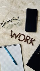Composition of Coffee Beans Forming Word WORK on Desk with Laptop and Stationery