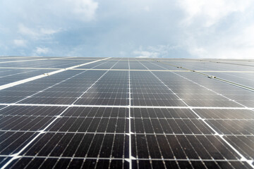 A low angle shows the surface of solar panels under a cloudy sky, generating sustainable energy....