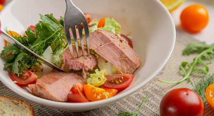 Salad with tuna and vegetables in a white bowl close-up