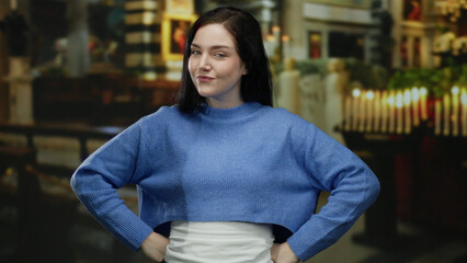Woman with brunette hair in a blue sweater stands confidently in a catholic church, surrounded by...