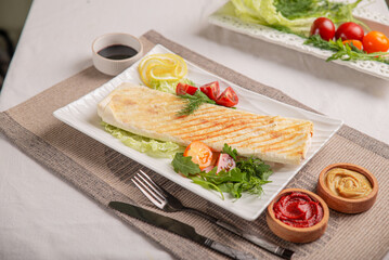 Lavash with vegetables and meat baked on a grill on a white plate on a served table