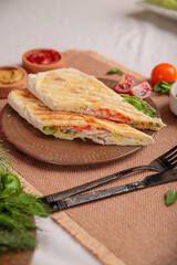 Lavash with vegetables and meat baked on a grill on a white plate on a served table