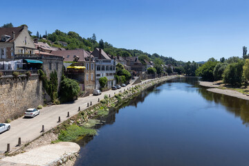 Beautiful summer view of the Vezere River a it passes through the town of Le Bugue in Perigord Noir, Dordogne, France. Clear blue sky, and copy spce above and below.