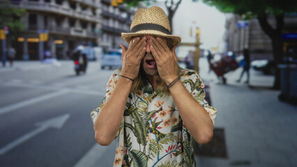 Man covering face with hands wearing floral shirt amid sunny busy urban street traffic; embarrassment.