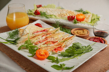 Wheat flatbread with vegetables and meat baked grilled on white plate on served table