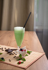 Mint cream cocktail in a tall glass goblet on a light wooden table